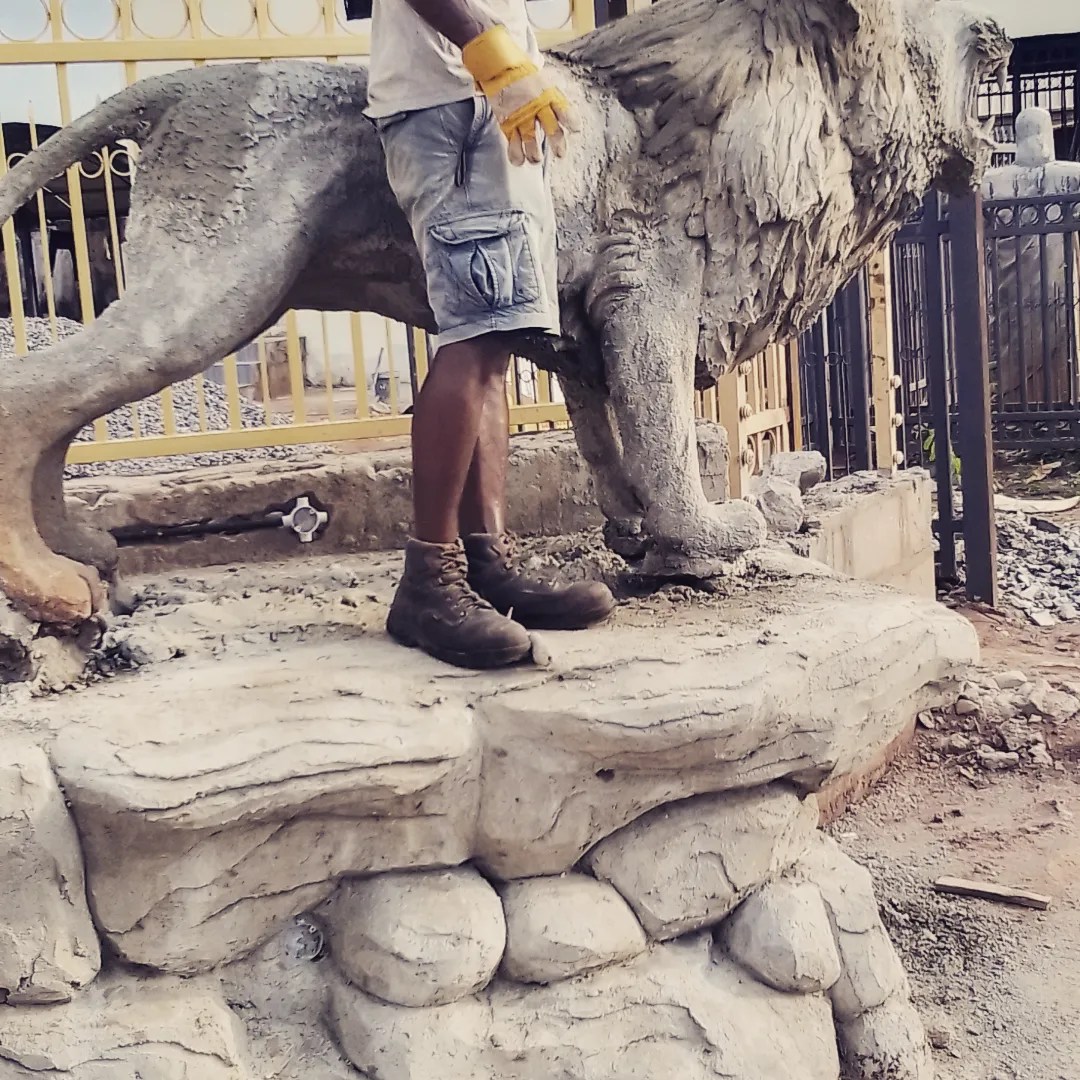 Henry Aziengbe standing beside his sculptural lion work