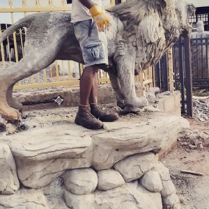 Henry Aziengbe standing beside his sculptural lion work